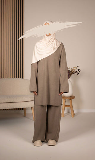 Gebreide set met lange tuniek en wijde broek in grijs, met witte hoofddoek over schouders.