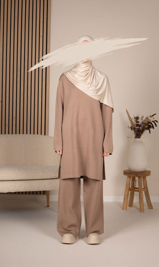 Gebreide set in taupe met lange tuniek en wijde broek, met witte hoofddoek over schouders.