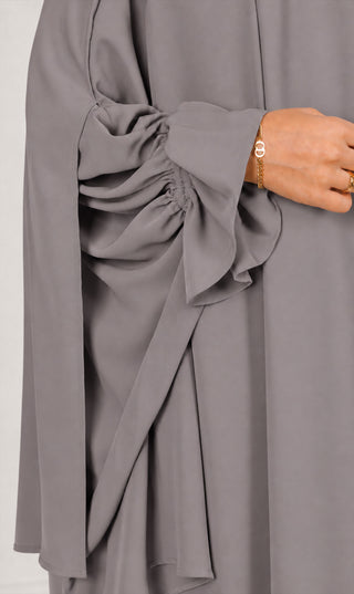 Grijze khimar met gerimpelde draperie rond de schouder en wijde manchetten