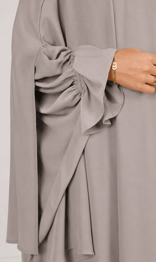Khimar detail met plooien en drapering aan de zoom, lichtgrijze stof