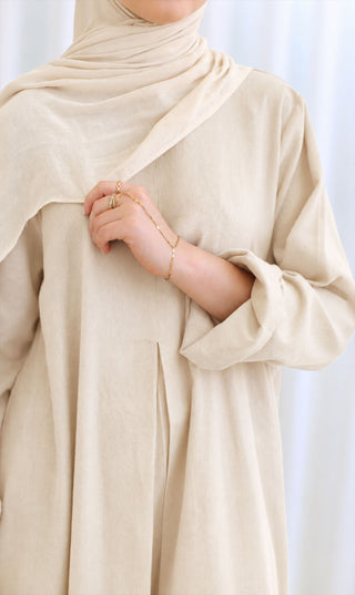 Linnen abaya crèmekleur met draperende hals en plooival bij de borst, lange mouw