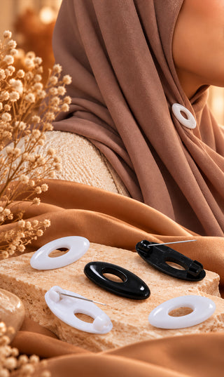 Veiligheidspelden set met witte en zwarte ovalen kopjes, op stof