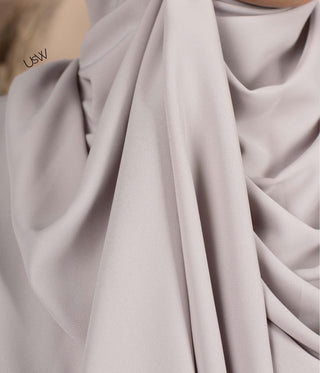 Detail van lichtgrijze hijabstof met diepe plooien en zachte draperie
