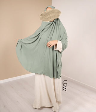 Pistachegroene khimar met grote draperie over schouders en crème onderrok zichtbaar